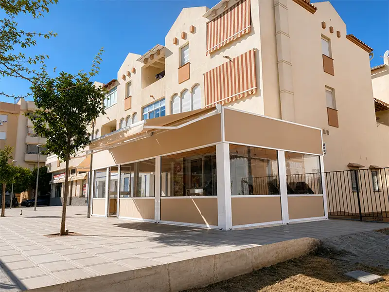 Cerramiento de terraza para restaurante con estructura de aluminio y toldo cortaviento con guías en Málaga.