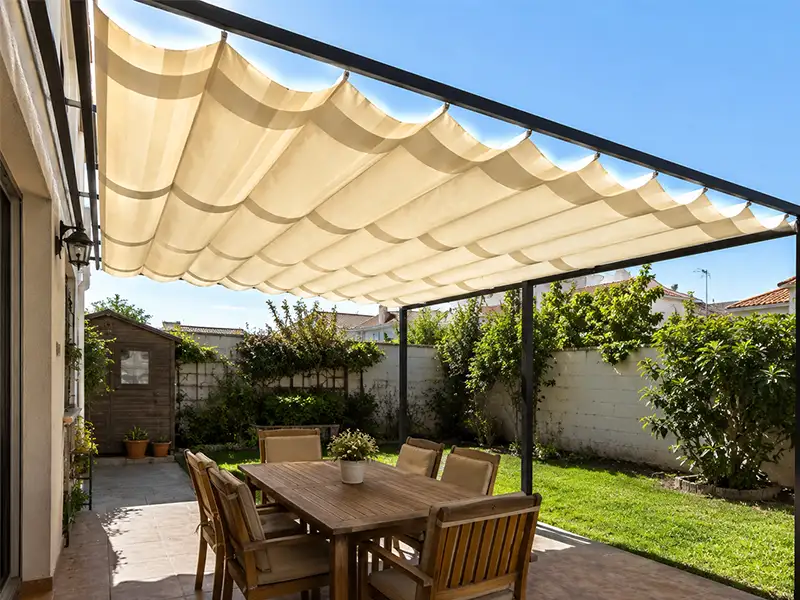 Pérgola de aluminio con palillería corredera instalada en un jardín de Málaga, creando una amplia zona de sombra sobre la terraza.