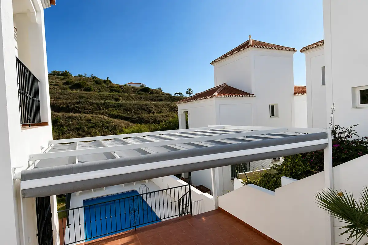 Pérgola de aluminio con toldo corredero parcialmente recogido instalada en terraza de vivienda en Málaga.