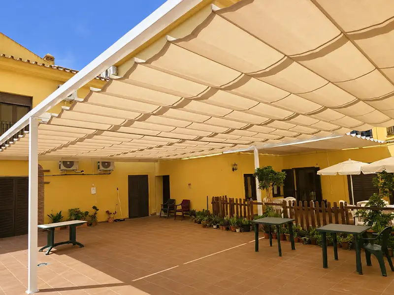 Toldo articulado con patas telescopicas color arena instalada en patio de restaurante en Málaga.