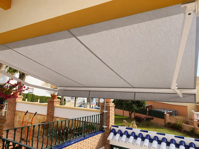 Toldo de brazos articulados y lona gris instalado en terraza de vivienda en Málaga.