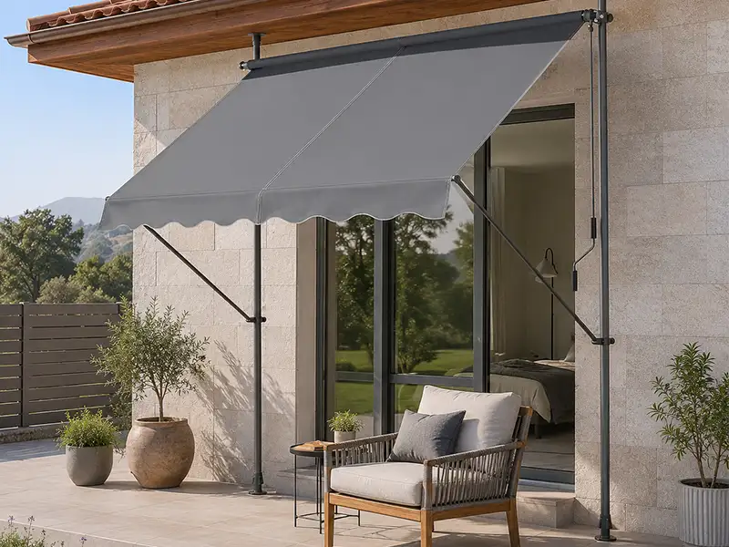 Toldo de brazos articulados con patas telescópicas y lona gris instalado en la terraza de una vivienda en la Costa de Granada.