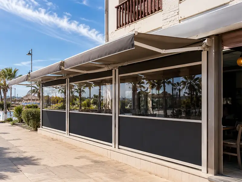 Terraza de restaurante en Marbella equipada con toldo cortavientos con guías y toldo articulado para proteger del sol, el viento y la lluvia.