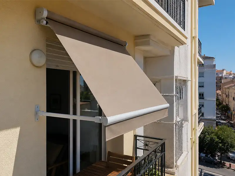 Toldo punto recto en Málaga con brazos laterales y lona beige instalado en un balcón para proteger del sol y mejorar el confort térmico.
