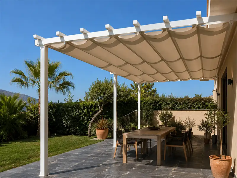 Pérgola de aluminio con palillería corredera instalada en el jardín de una vivienda en Málaga, proporcionando sombra regulable sobre la zona de comedor exterior.