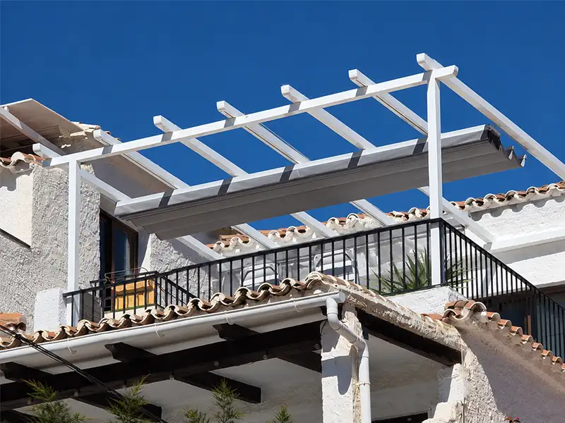 Pérgola de aluminio con estructura para palillería instalada en el balcón de una vivienda en Nerja, diseñada para crear una zona de sombra elegante y resistente.