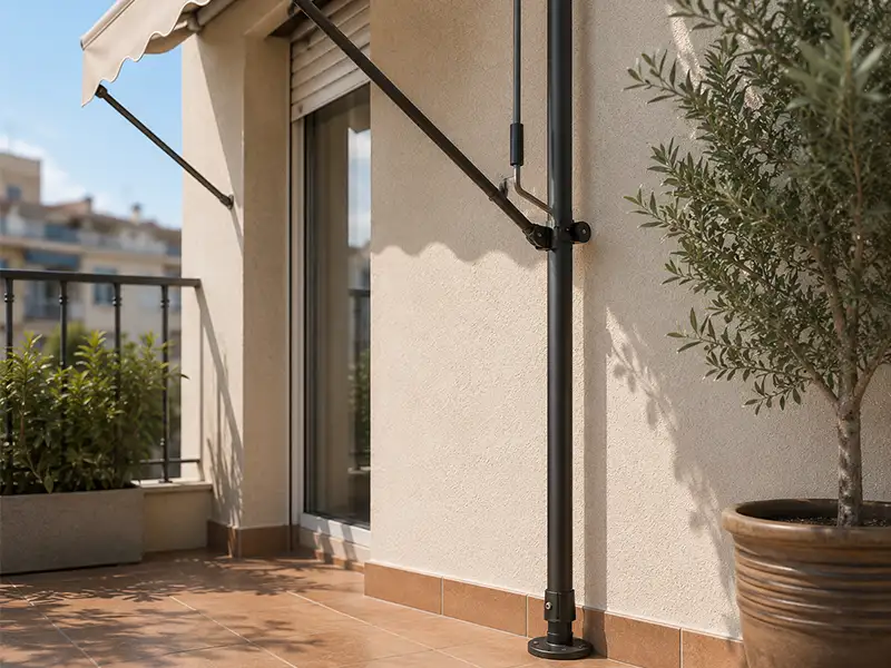 Detalle de un toldo de brazos articulados con pata telescópica instalado en la terraza de una vivienda para proporcionar sombra y estabilidad.