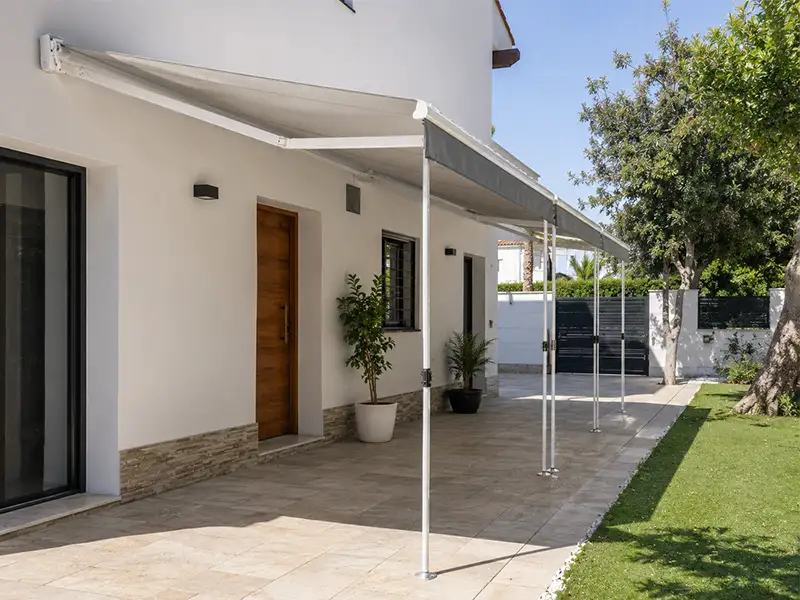 Toldo de brazos articulados con patas telescópicas instalado en la terraza de una vivienda unifamiliar en Nerja, Málaga.