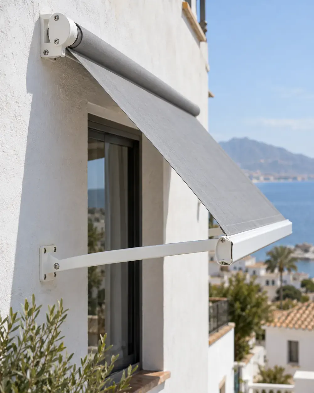 Brazo y soporte de toldo punto recto Brazo recto y soporte de aluminio blanco de un toldo punto recto con lona gris sobre una ventana