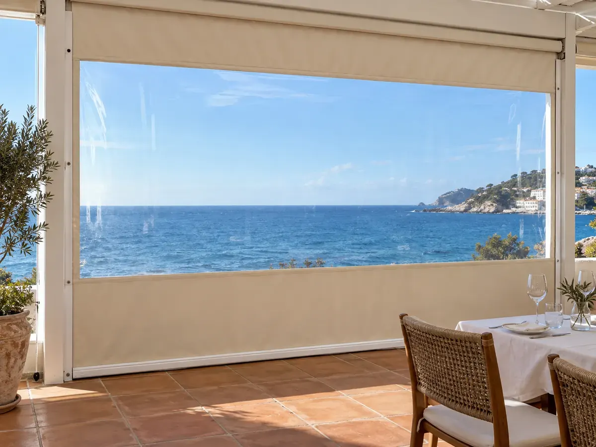 Cortavientos con ventana transparente Cortavientos con ventana transparente que deja ver el mar desde la terraza de un restaurante