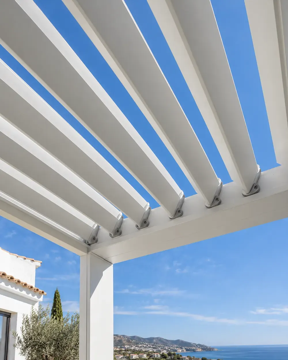 Lamas orientables de pérgola bioclimática Lamas orientables de aluminio blanco de una pérgola bioclimática entreabiertas