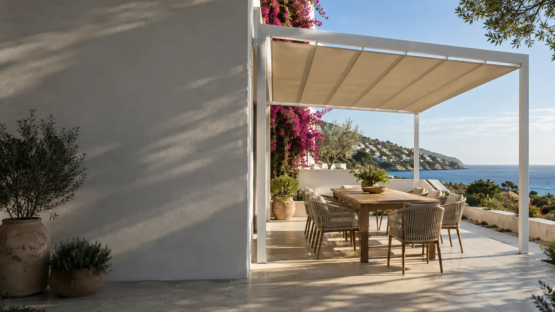 Pérgolas de aluminio en Málaga Pérgola de aluminio en Málaga con toldo corredero de lona crema sobre el comedor exterior de una casa con vistas al mar