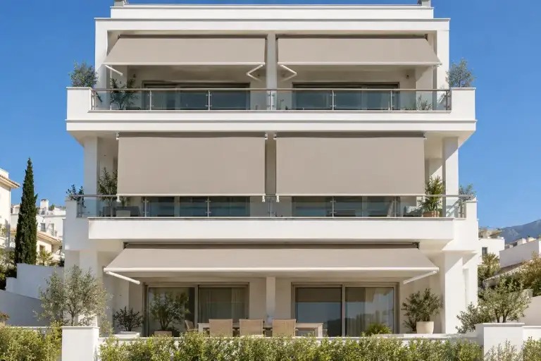 Toldo enrollable: fachada de un edificio con toldos de lona beige en todos los balcones