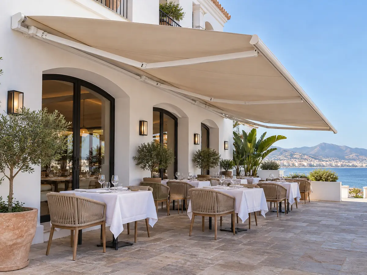 Toldo grande para terraza de restaurante Toldo de gran tamaño con lona beige sobre la terraza de un restaurante frente al mar