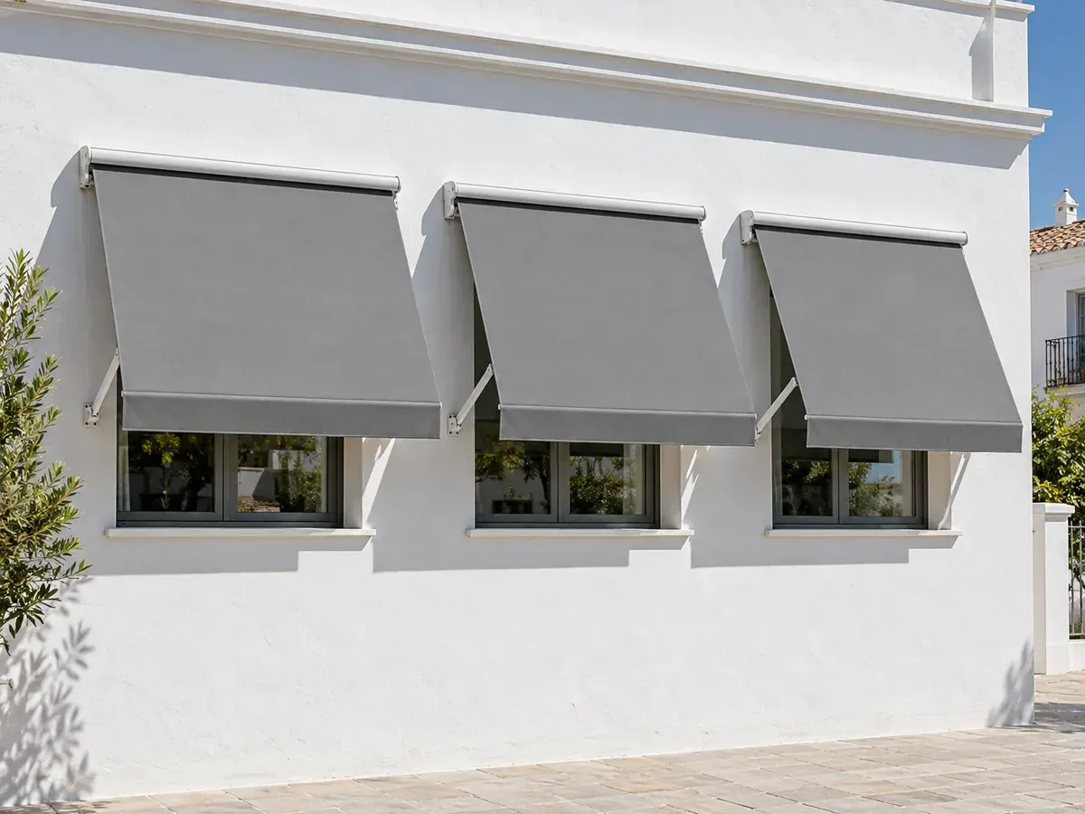 Toldo retráctil punto recto motorizado con lona gris en tres ventanas de una vivienda
